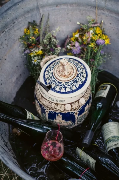 Weinprobe Mosel: gekühlte Rieslingflaschen und Steinkrug mit Blumen – Picknick im Weinberg