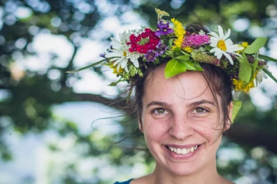 Weinprobe Mosel: lächelnde Teilnehmerin mit Blumenkranz im Grünen, Porträt